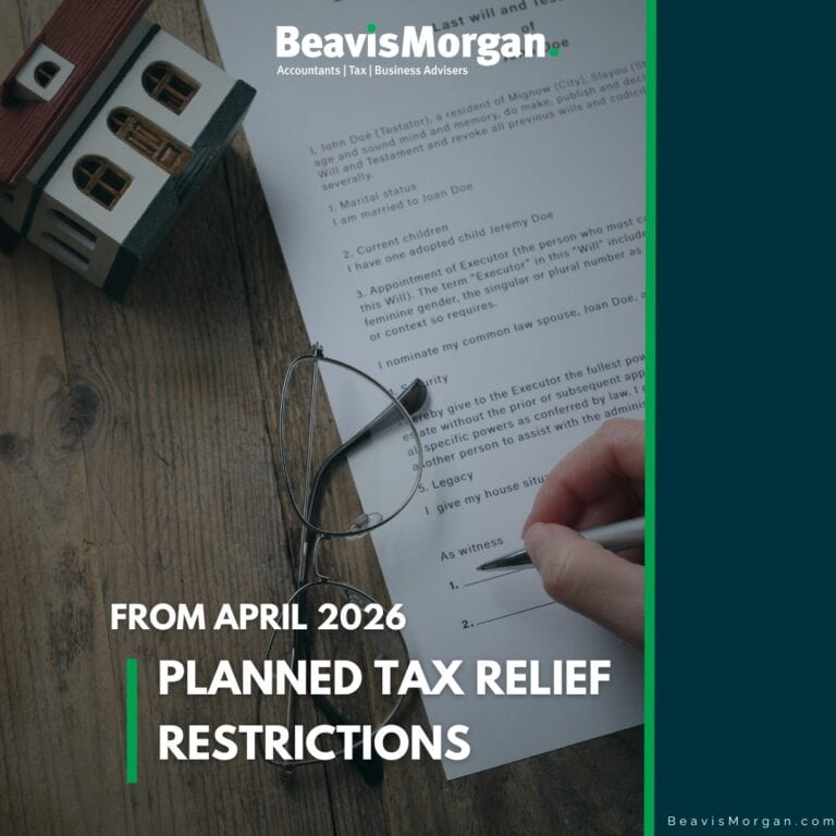 A person signing their name on a document with a small model house and glasses beside them.